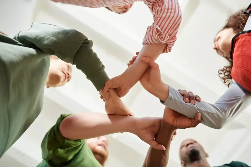 close-up of lots of arms holding each other, all of different colours, representing diversity and inclusion in recruitment