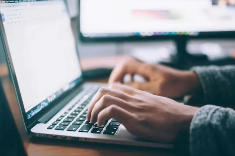 Hands on a laptop keyboard building a candidate database online