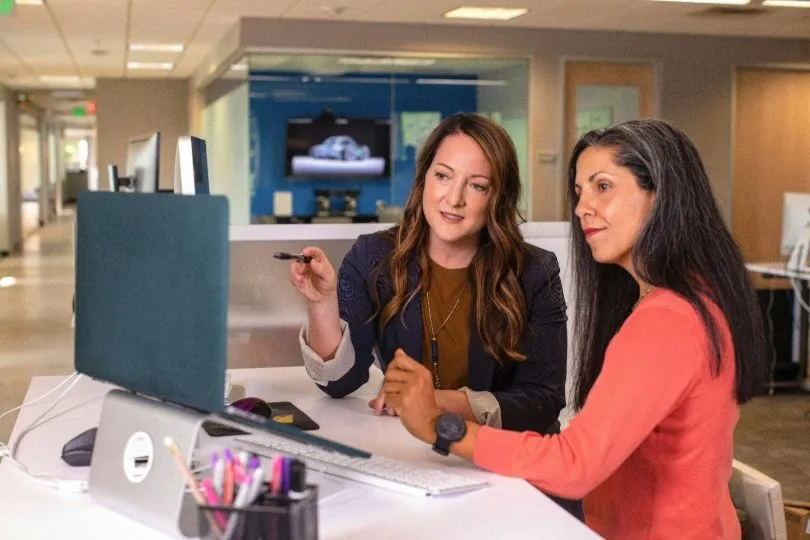 Two women look at a candidate database on a computer screen